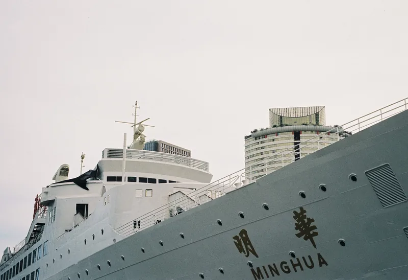 A white ship moored beside waterfront buildings.