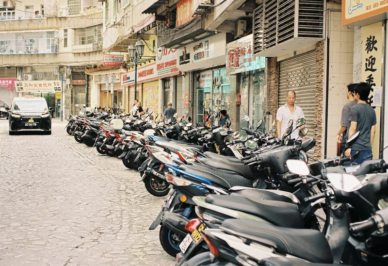Rows of parked scooters along a shopping street.
