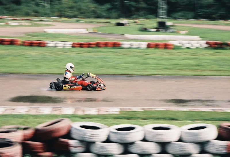 A go-kart passing red and white tire barriers.