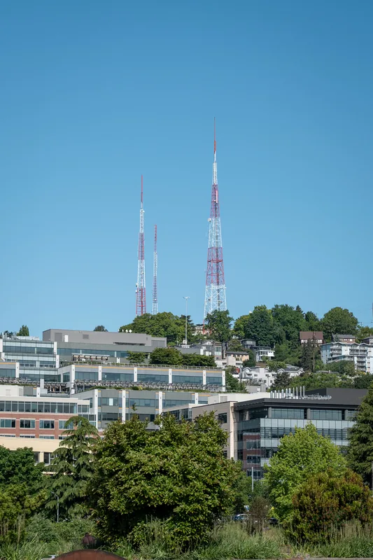 City buildings and communication towers above trees.