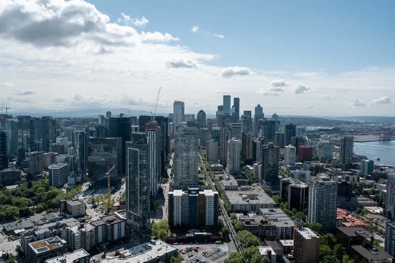 A city skyline beneath scattered white clouds.