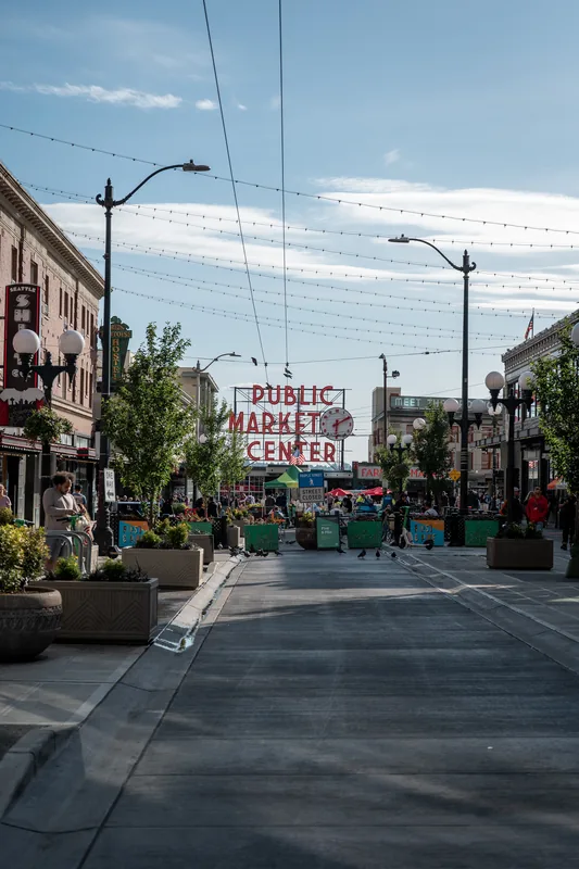 A sloping street lined with shops and overhead wires.