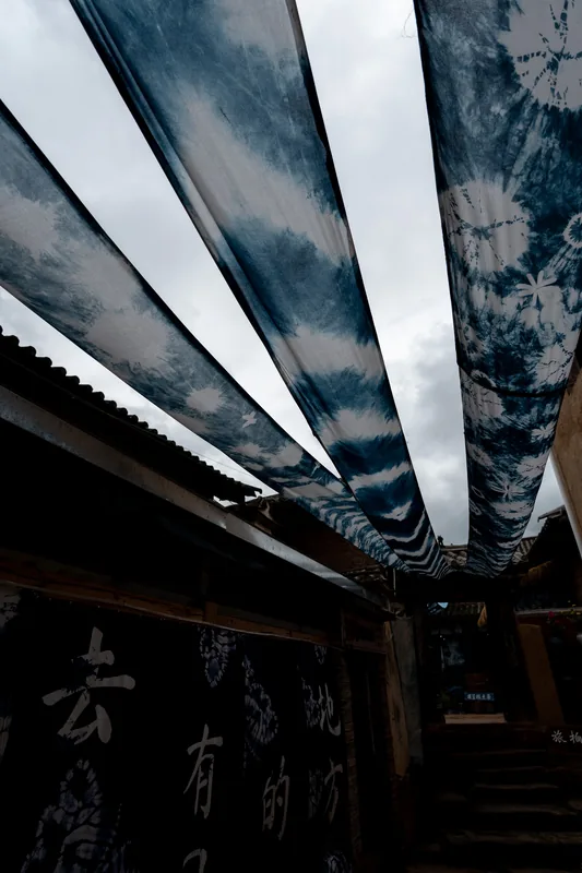 Blue and white fabric suspended over a narrow lane.