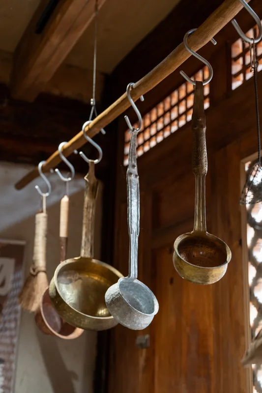 Brass ladles suspended from a wooden beam.